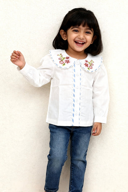 Capri organic cotton girls blouse flat lay showing GOTS-certified white cotton fabric and blue lace button placket